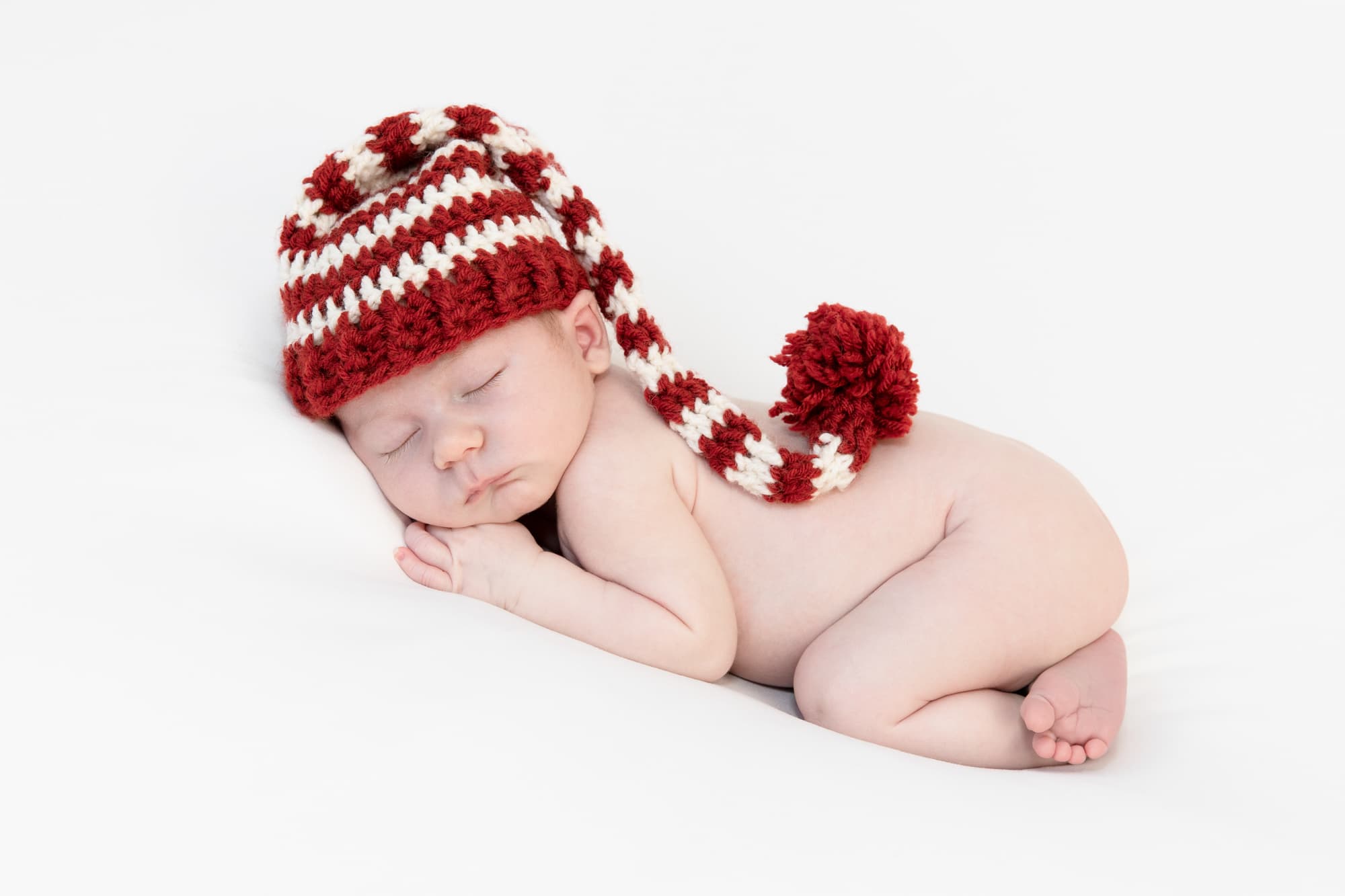 newborn in red and white striped hat