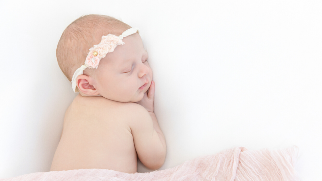 Image of newborn in pink wrap with headband during newborn photography shoot jane goodrich photography studio in larchmont, NY