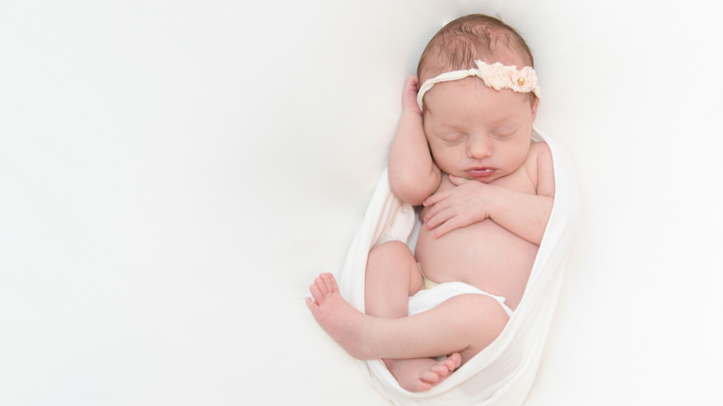 Image of newborn in white wrap with headband during newborn photography shoot jane goodrich photography studio in larchmont, NY