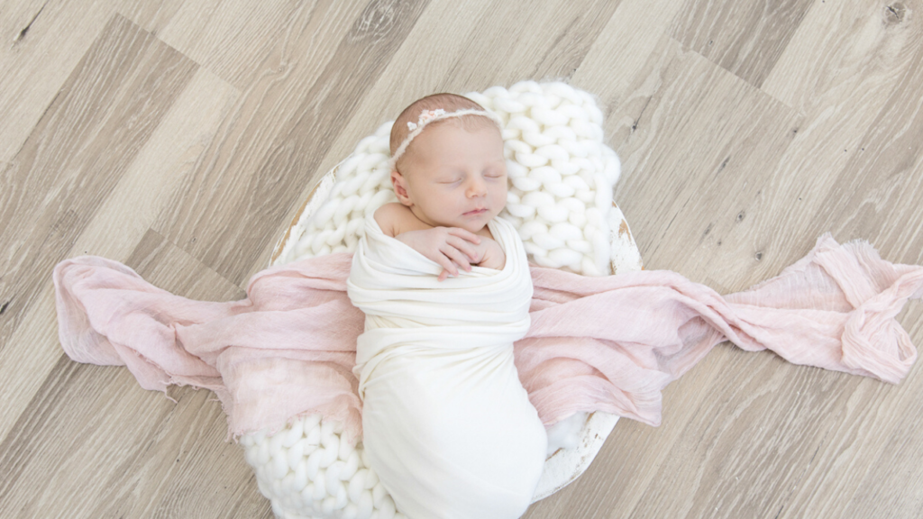 Image of newborn in white wrap with pink accent during newborn photography shoot jane goodrich photography studio in larchmont, NY
