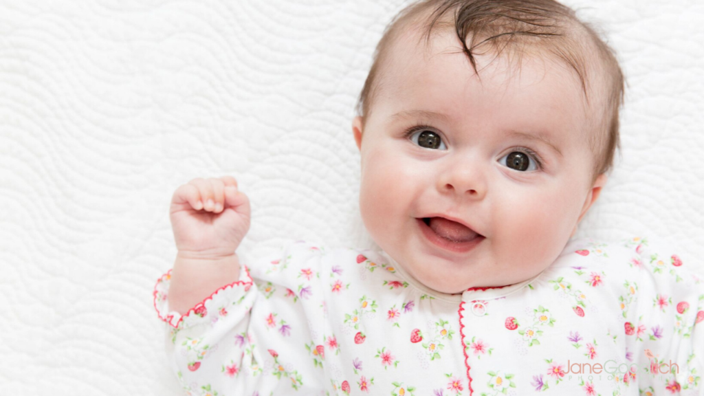 smiling newborn in flowered top on white background