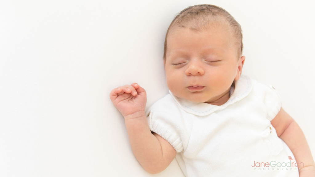 picture of newborn in white clothes on white background jane goodrich photography