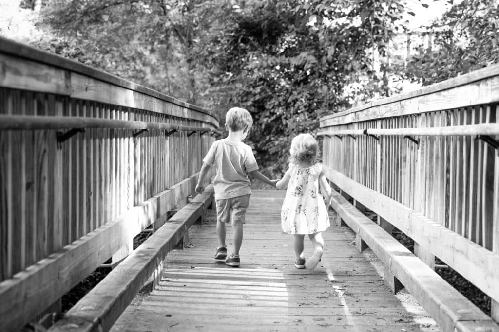 black and white outdoor sibling photograph on bridge