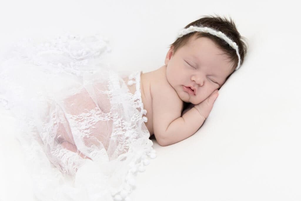 newborn girl in white lace wrap studio portrait in Scarsdale NY