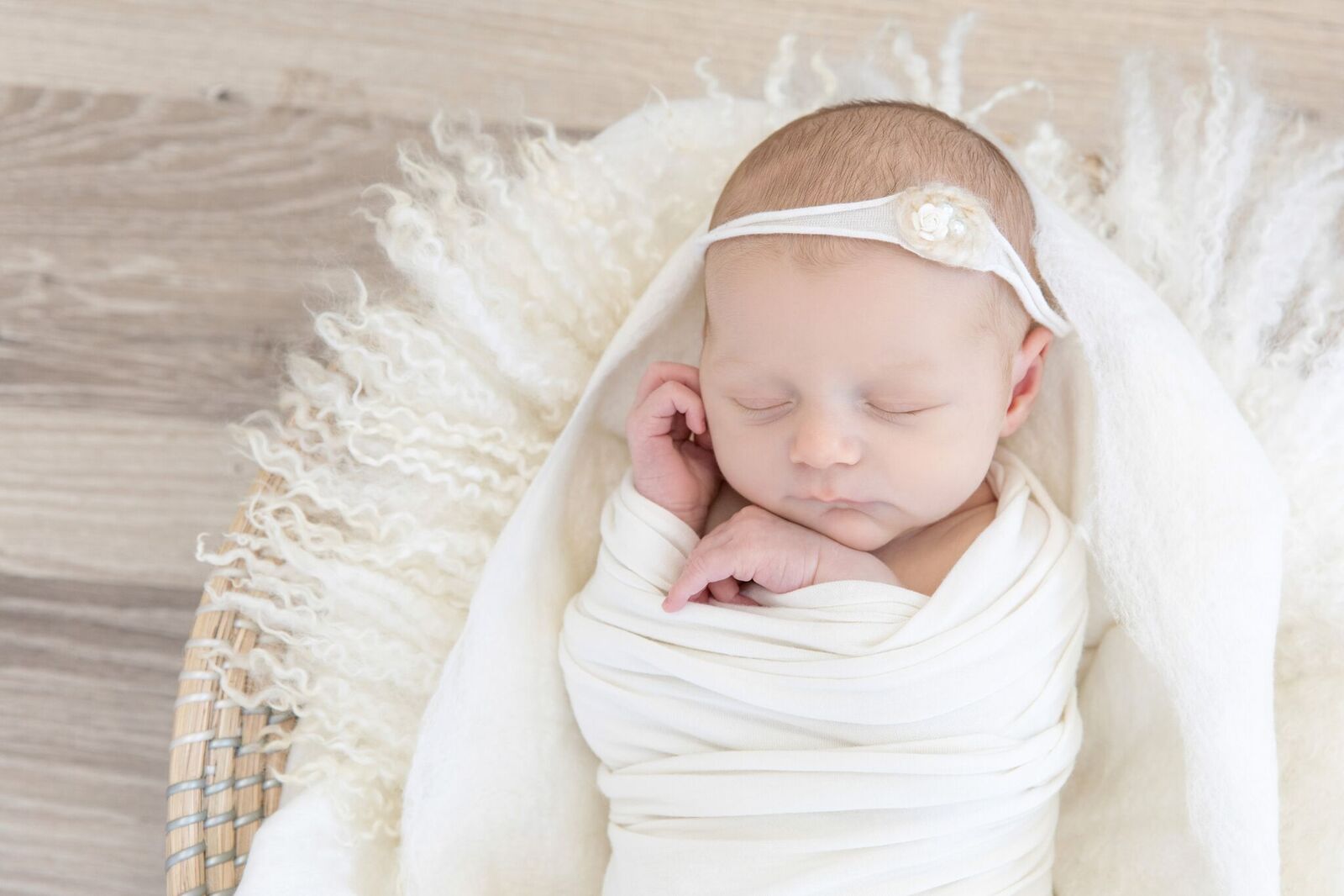newborn girl wrapped in white blankets